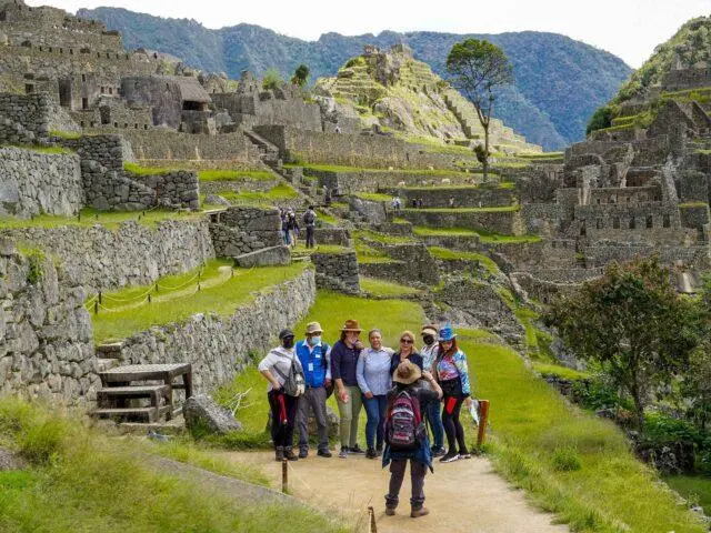 Group of tourists following a local guide through stone terraces
