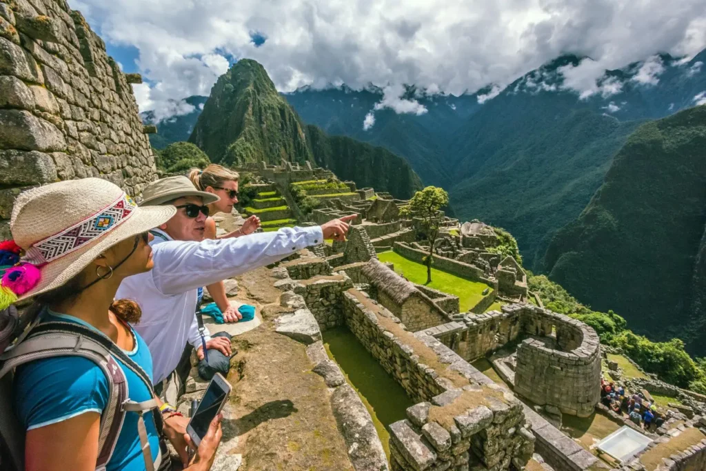 Group of tourists following a local guide through the stone terraces of Machu Picchu